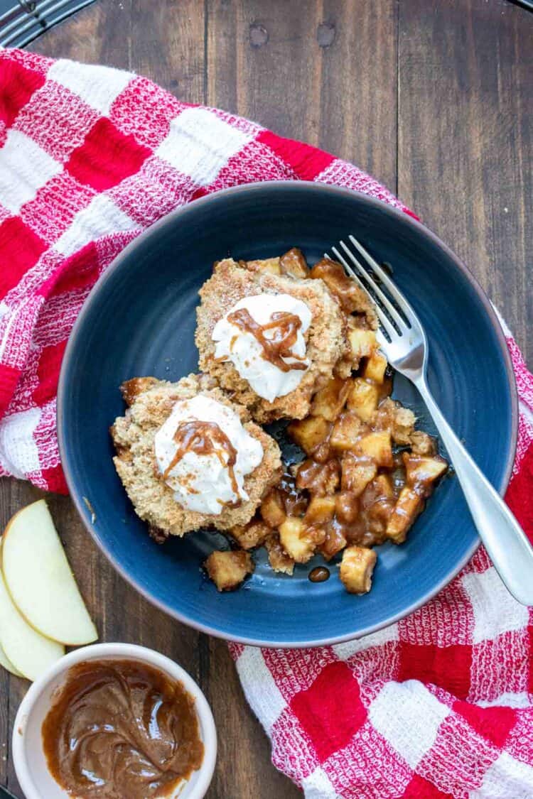 Dark blue bowl filled with apple cobbler on a red checkered towel