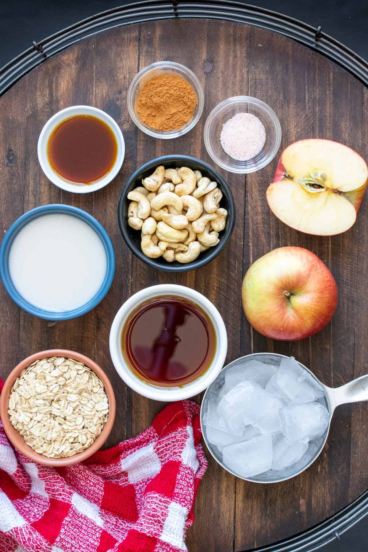 Ingredients to make a dairy free apple smoothie on a wooden surface with a red checked towel.