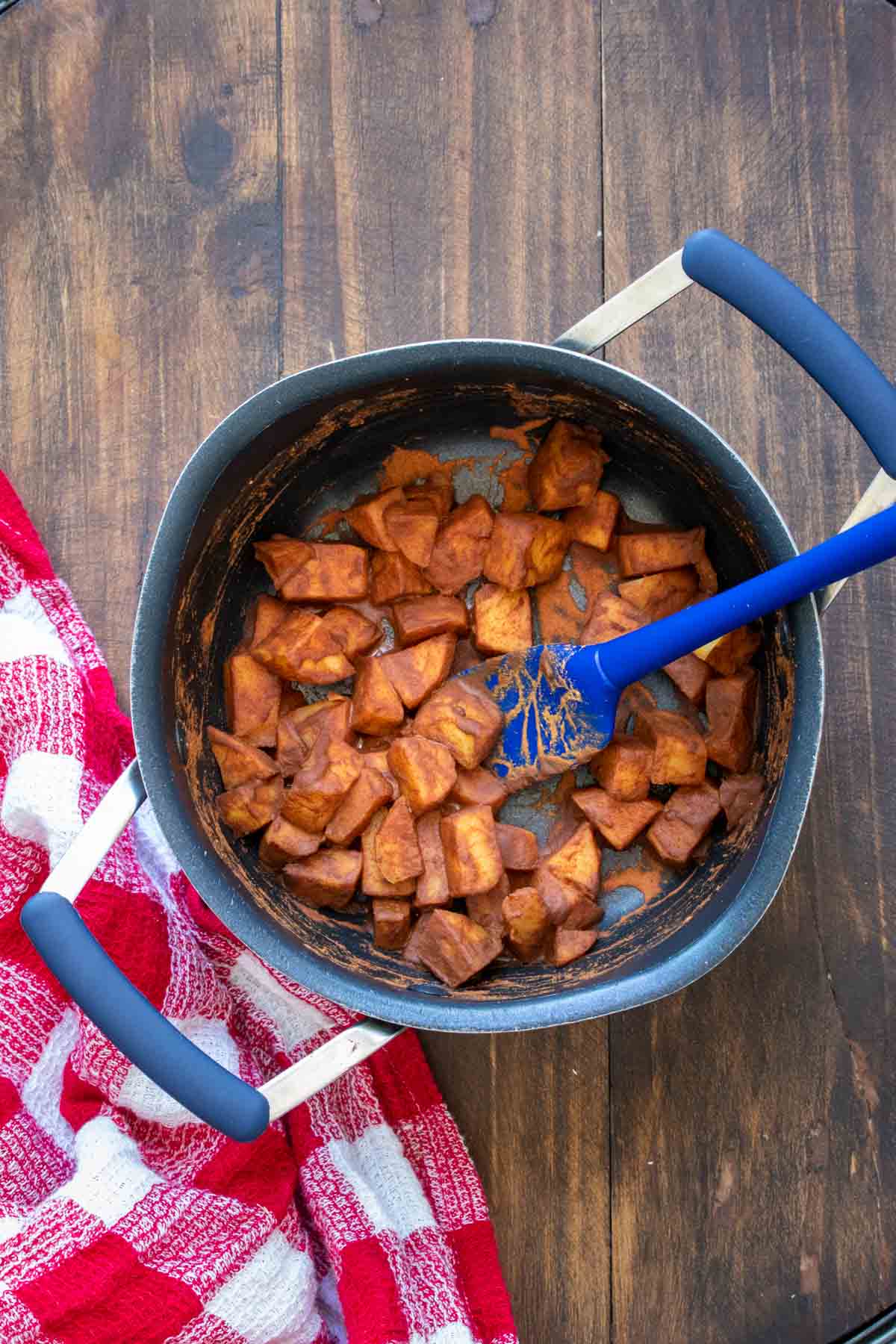 Blue spatula mixing apples and cinnamon in a pot