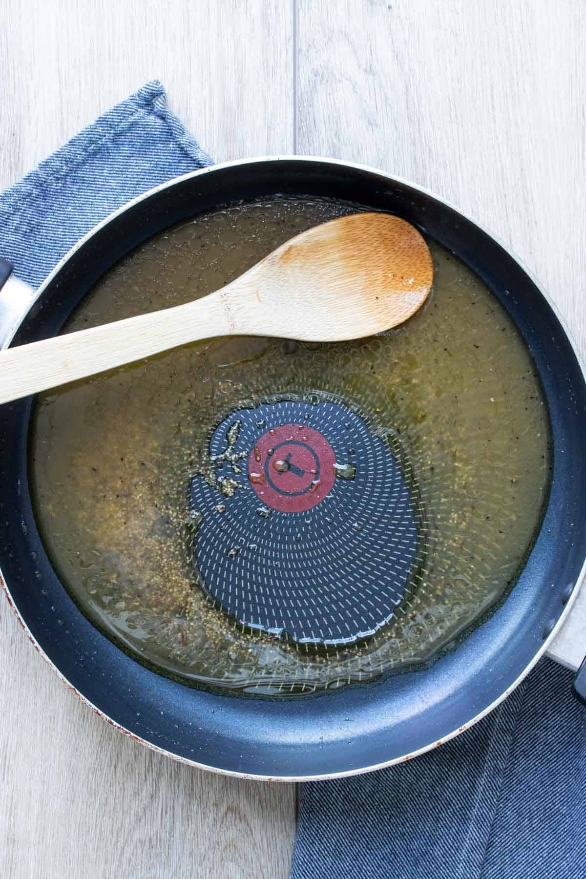 Wooden spoon mixing mixing broth in a saute pan