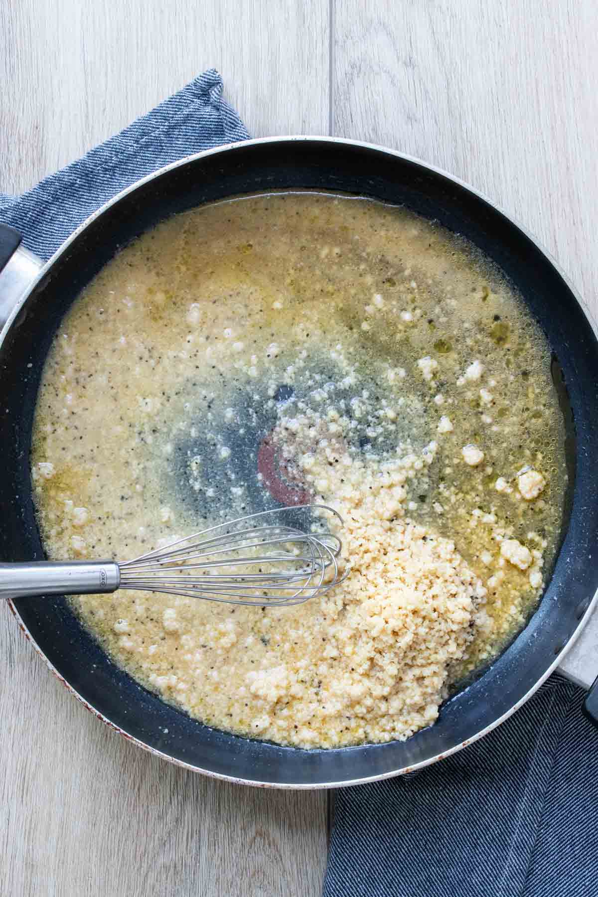 Whisk mixing parmesan into a broth