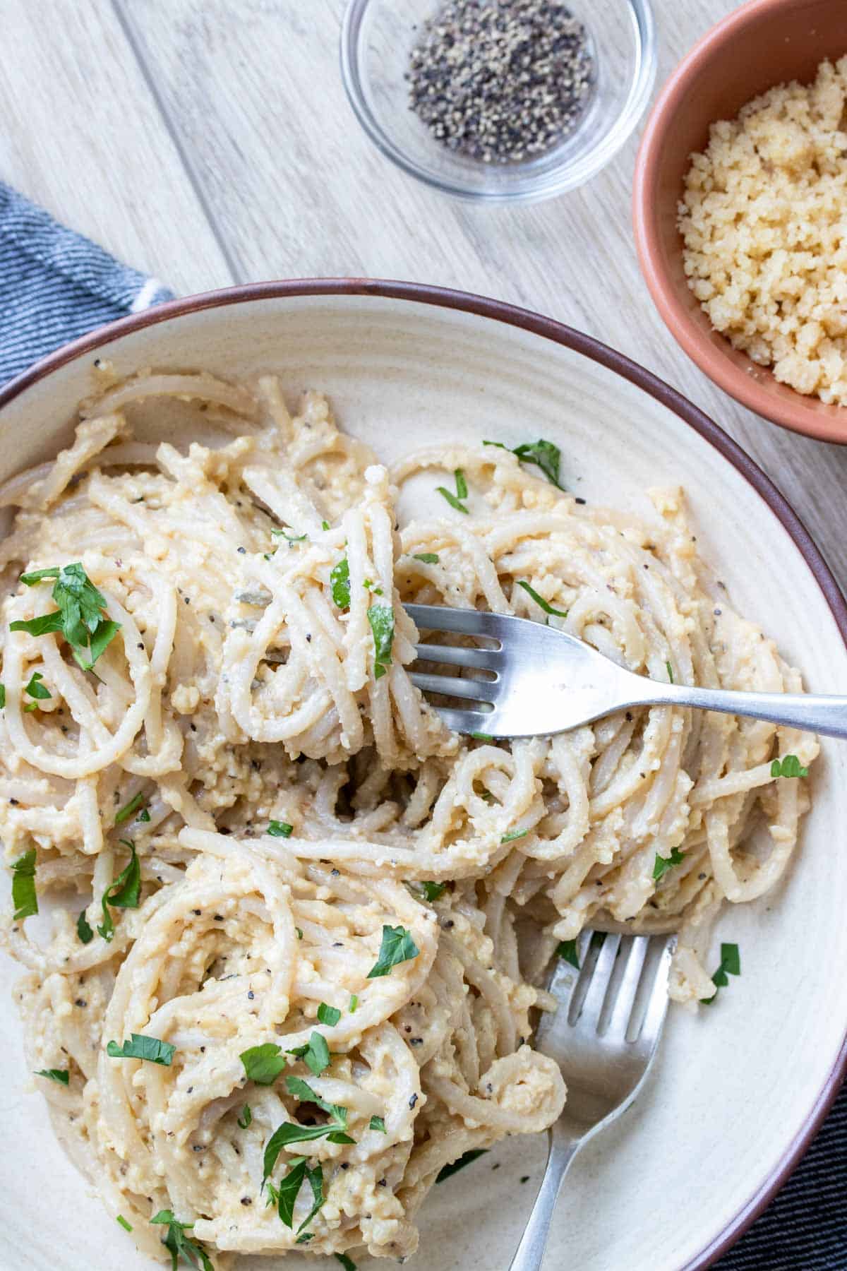 Fork twirling spaghetti with a creamy like sauce in a cream colored bowl