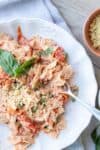 Fork getting a bit of feta and tomato pasta from a white bowl