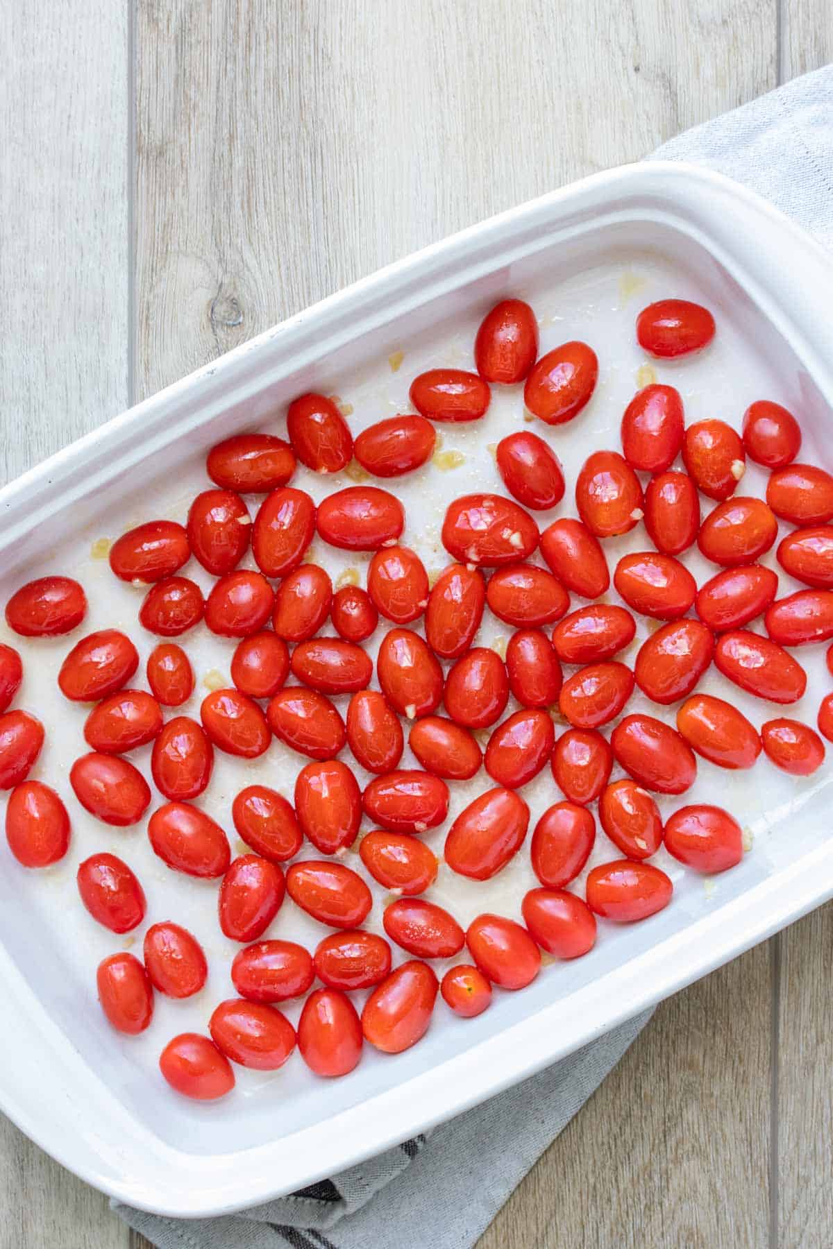 Grape tomatoes spread out in a white baking dish