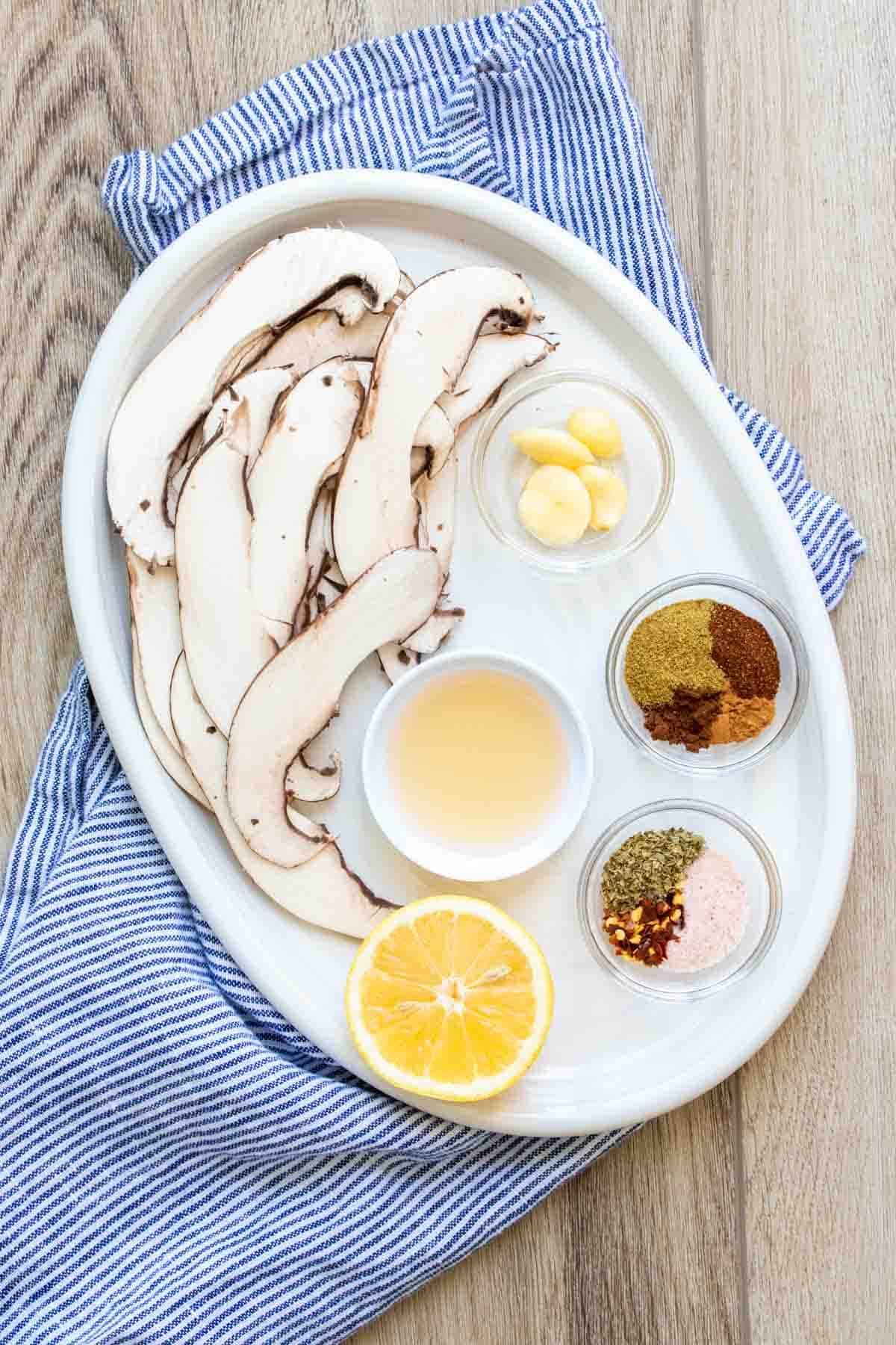 White platter with slices of portobello, lemon and seasonings.