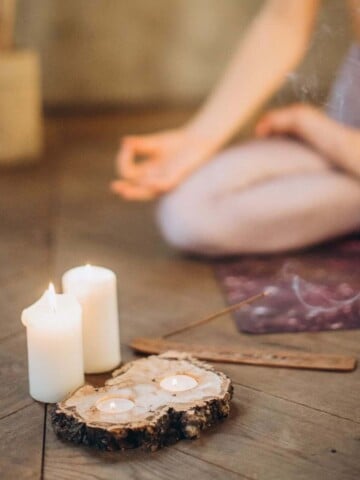 Lit candles next to a piece of wood on a wooden surface