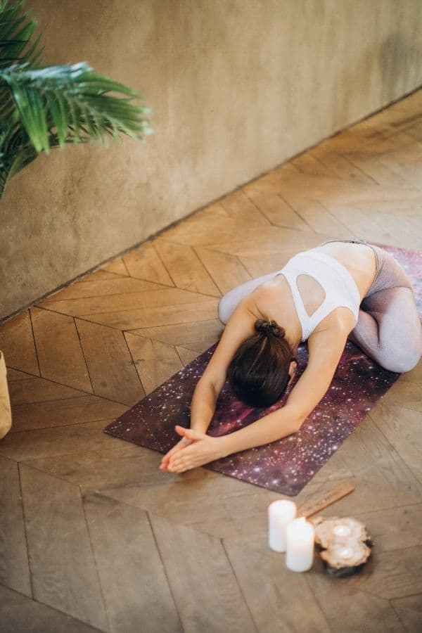 Woman laying forward in a cross legged position on a yoga mat