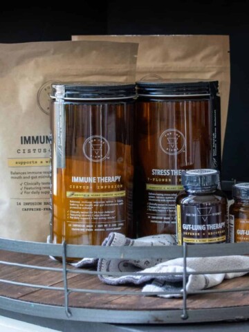 Two brown bags and four amber containers of supplements on a wooden tray