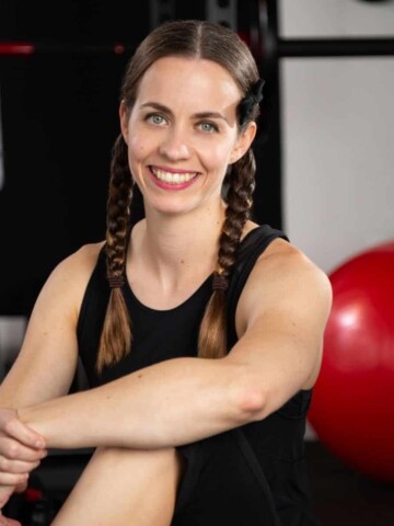 Woman sitting with her arm on her knee next a large red exercise ball