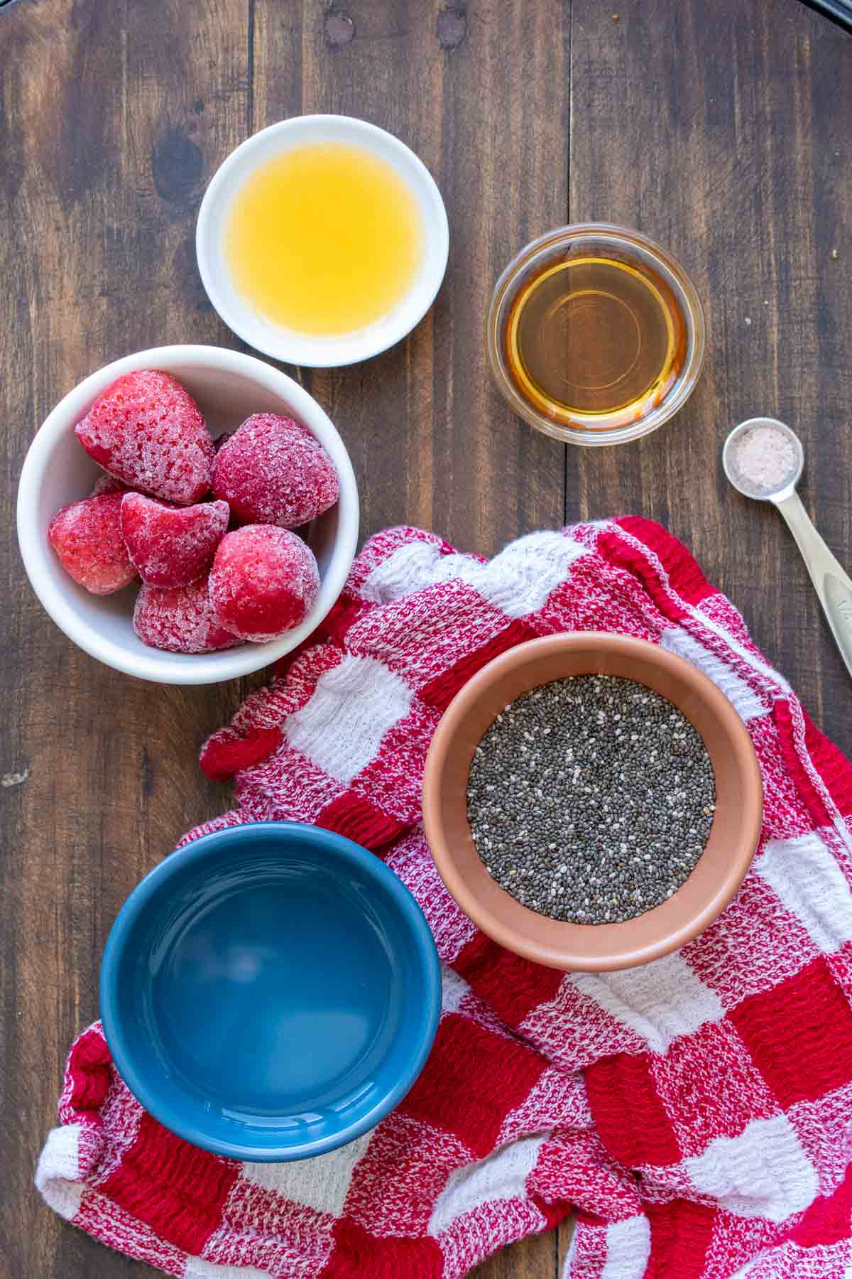Colored bowls with ingredients to make chia seed jam on a red checkered towel
