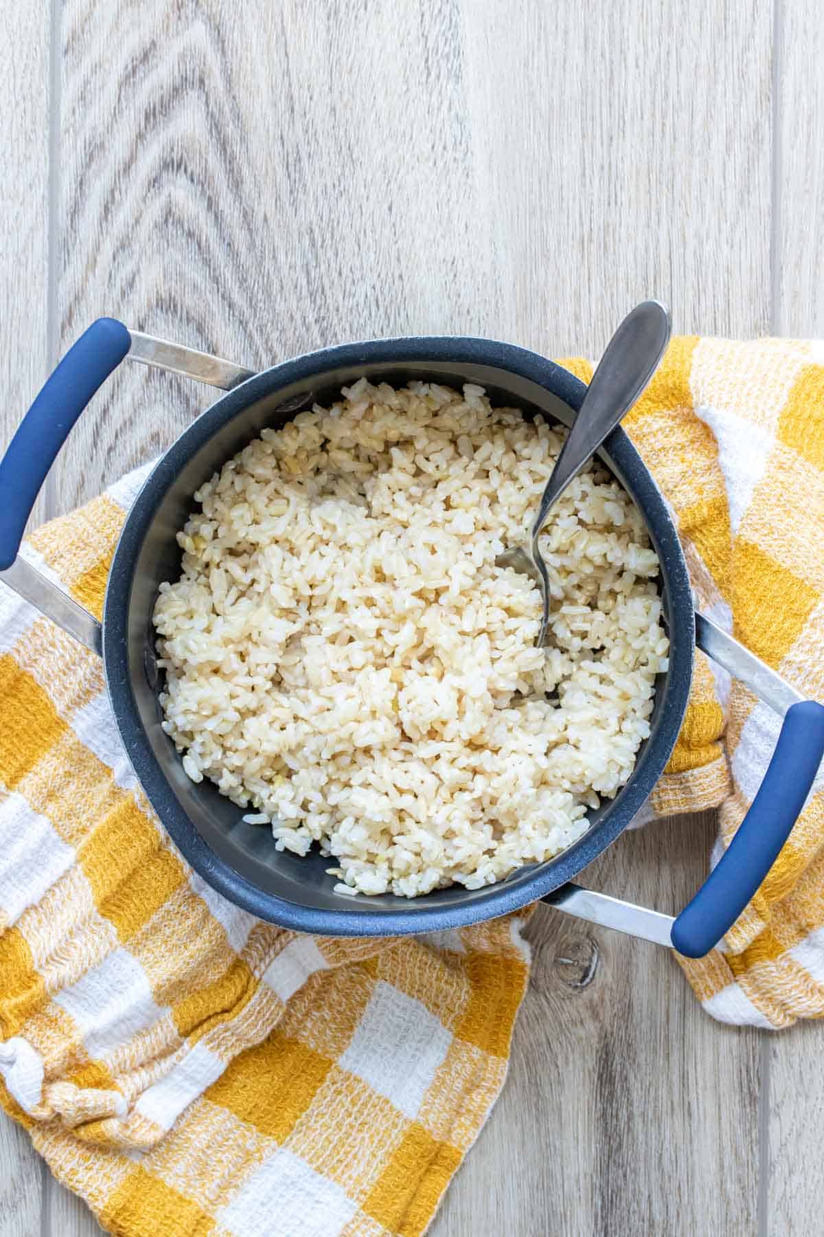 Yellow and white checkered towel with a pot of rice on it.