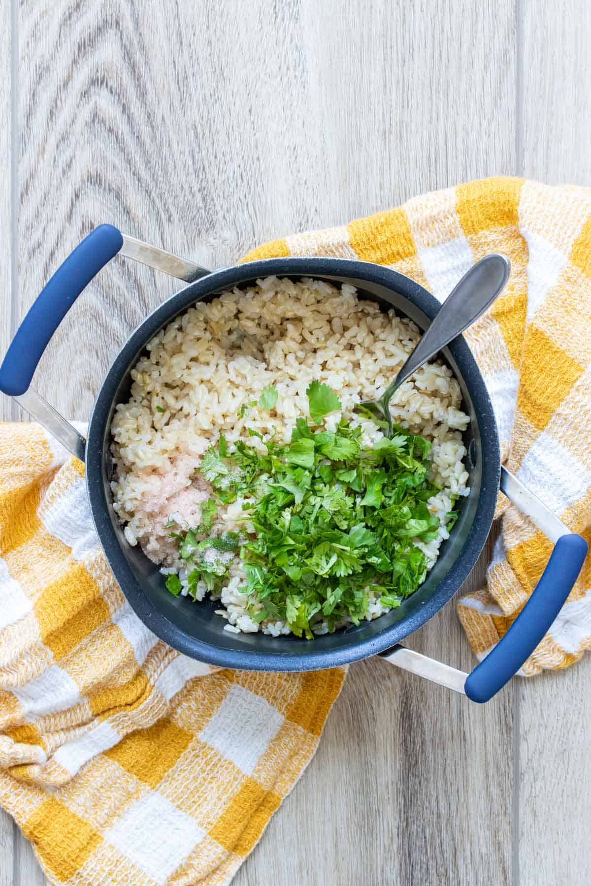 Yellow checkered towel with a pot of rice covered in chopped cilantro on top