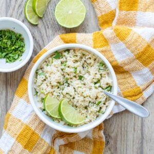 Bowl filled with chopped cilantro and rice mix and sliced limes.