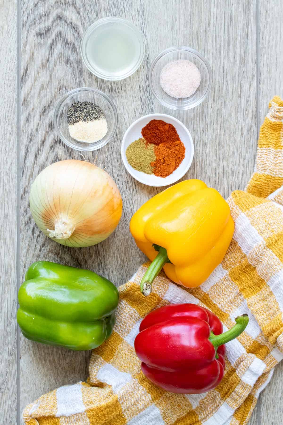 Ingredients needed to make Mexican spiced fajita veggies on a wooden surface