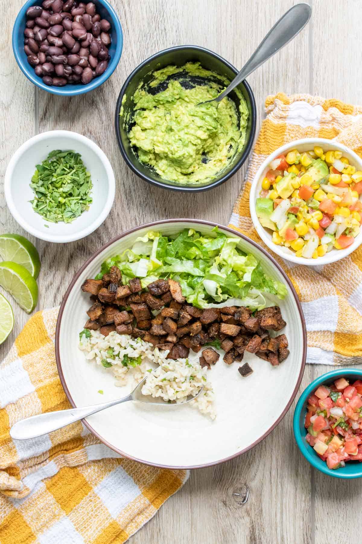 White bowl with piles of lettuce, beans and rice in a row inside.