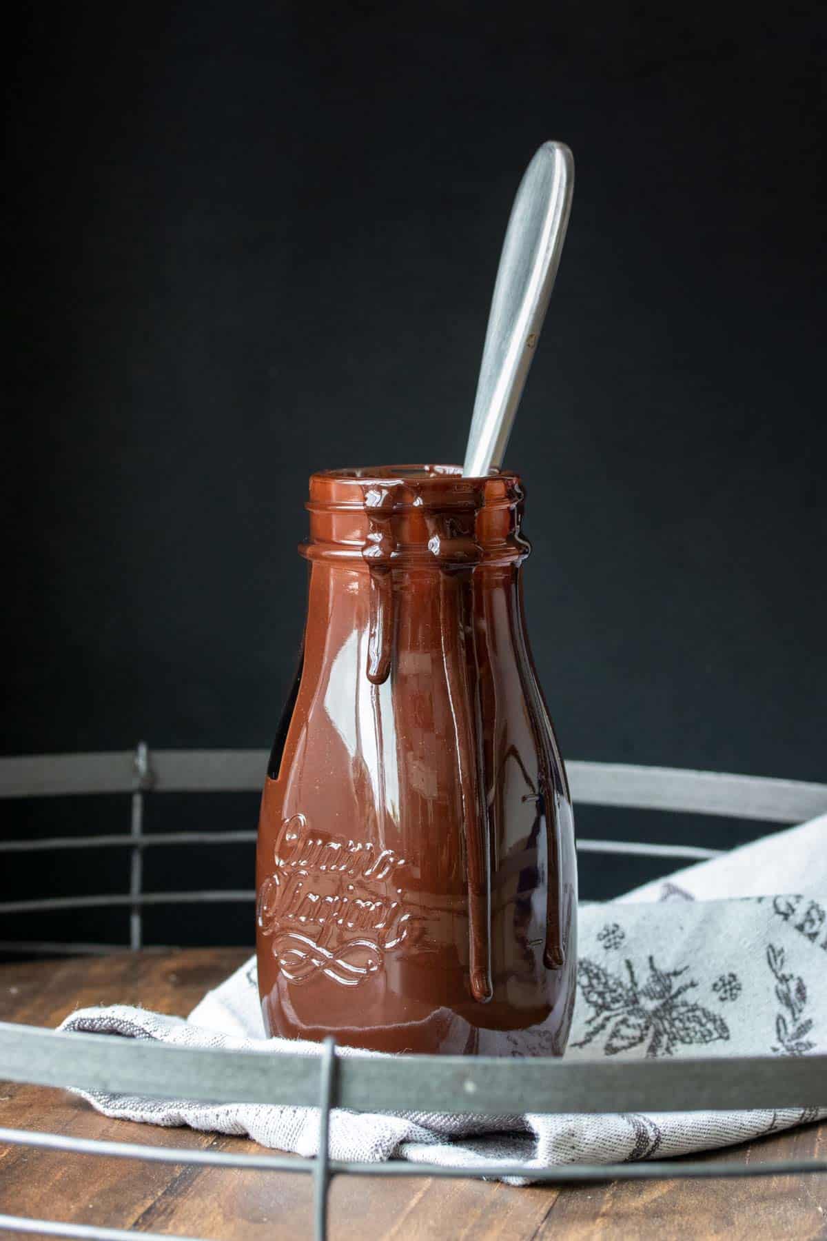 Glass bottle filled with chocolate sauce on a wooden tray