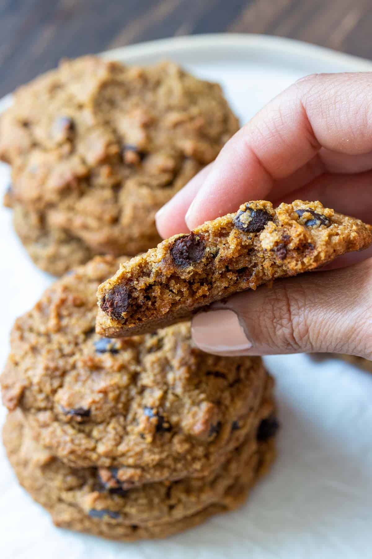 Hand holding a half eaten cookie with chocolate chips so you can see the soft middle