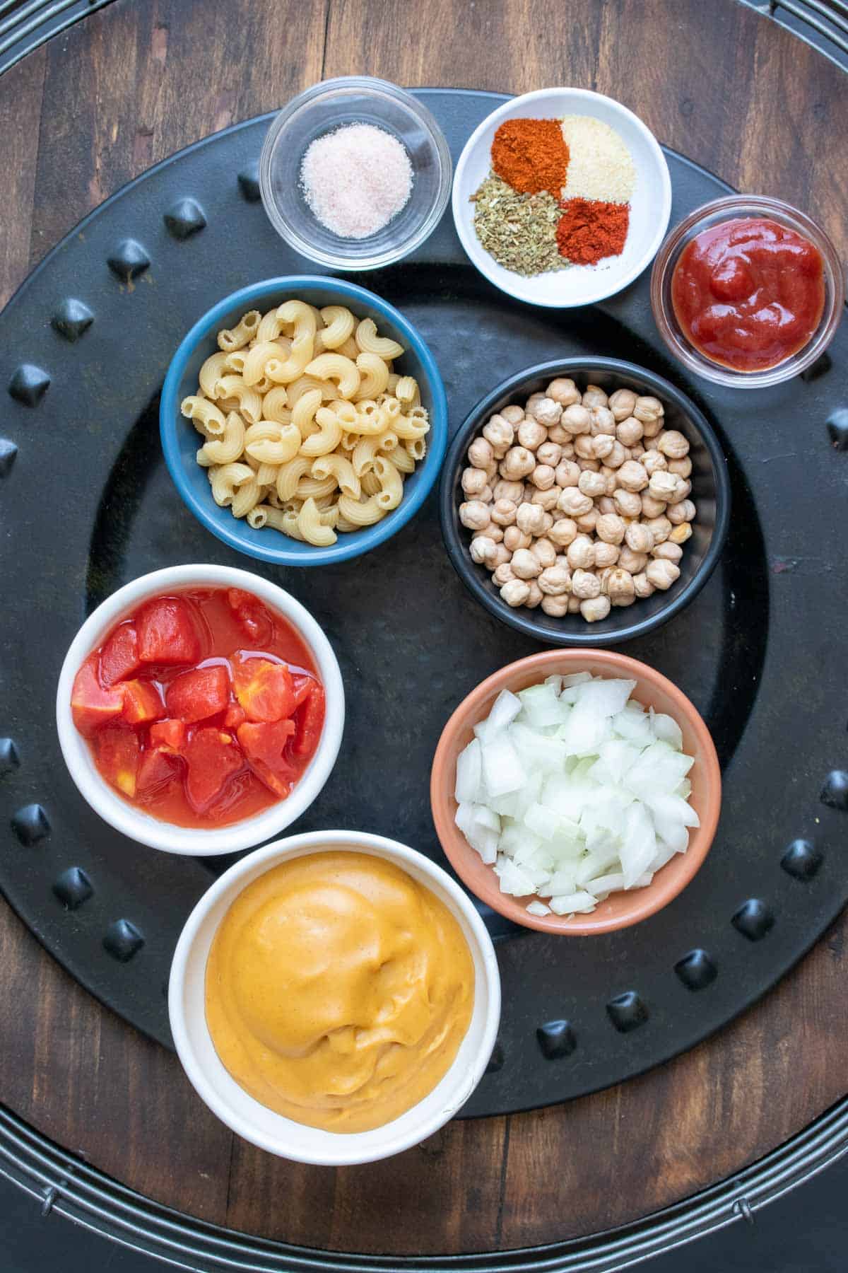 Black platter with ingredients needed to make a vegan hamburger helper macaroni dish