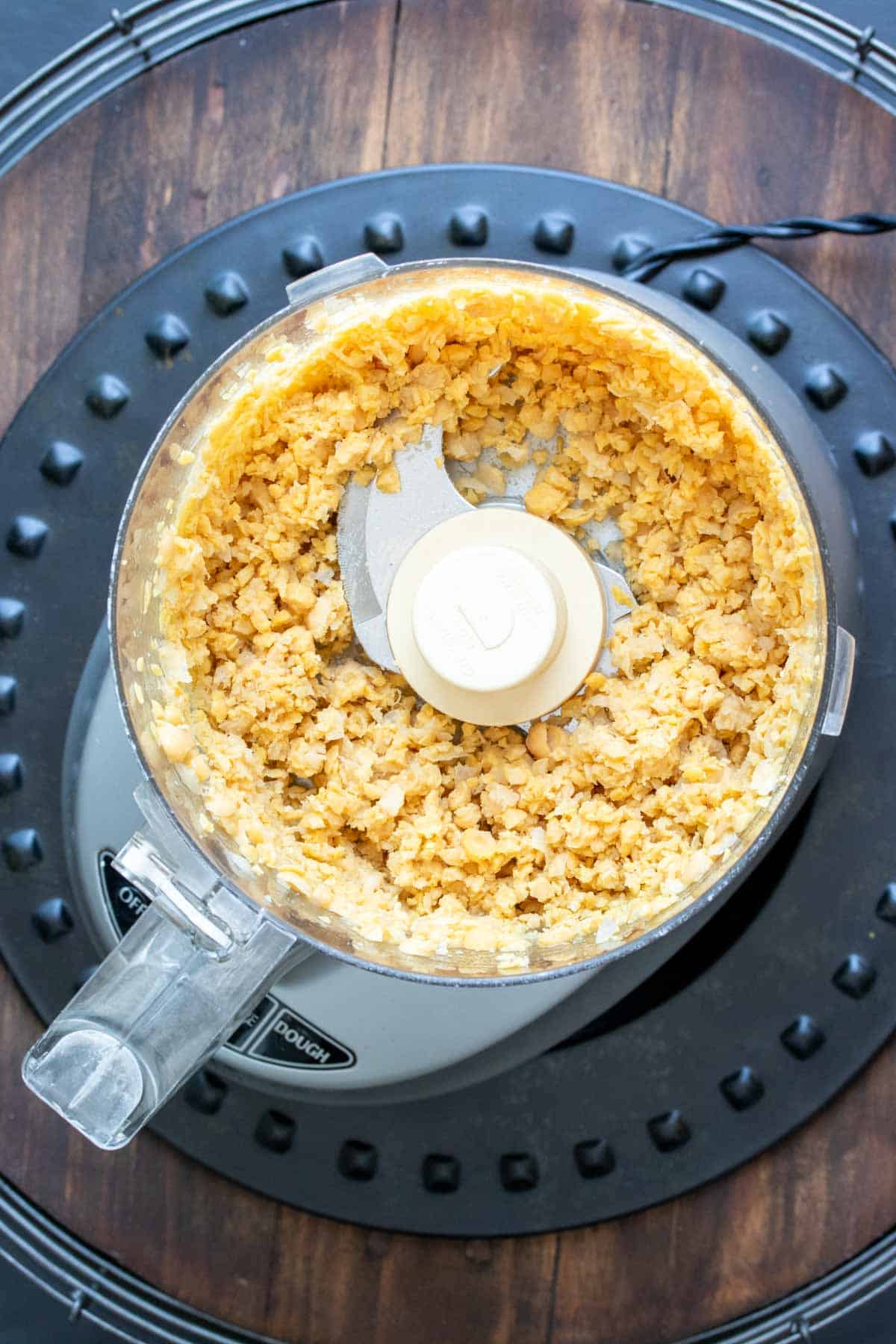 Top view of a food processor with chopped chickpeas in it
