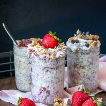 Three glass jars filled with different flavors of overnight oats sitting on a pink napkin on a wooden surface