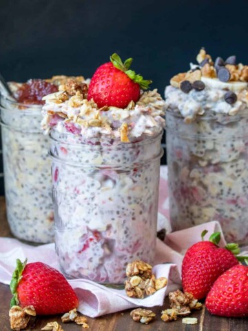 Three glass jars filled with overnight oats flavors of berry, chocolate chip and peanut butter and jelly