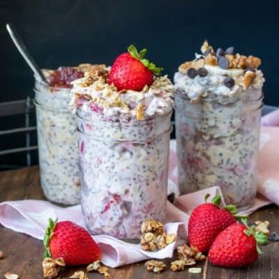 Three glass jars filled with overnight oats flavors of berry, chocolate chip and peanut butter and jelly
