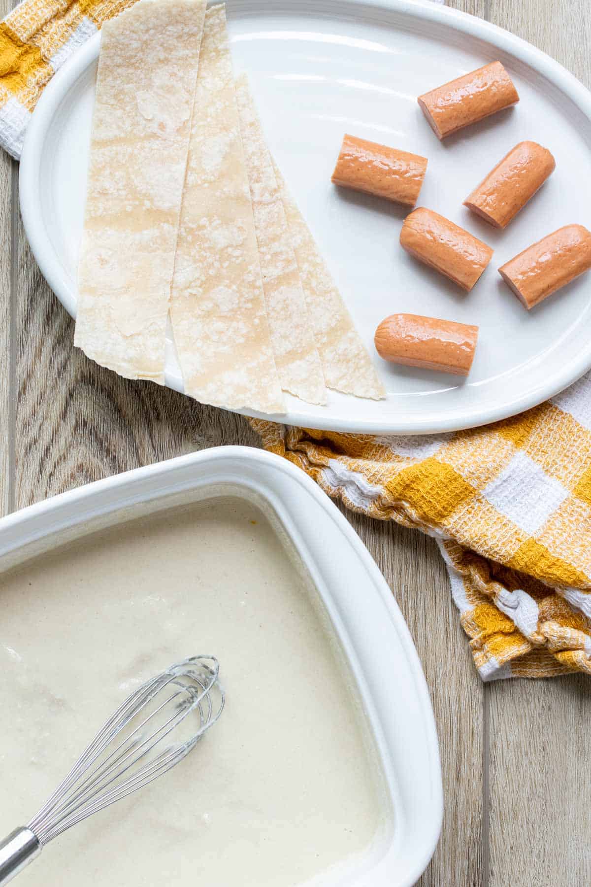 Cut hot dogs and tortilla strips on a plate next to batter.