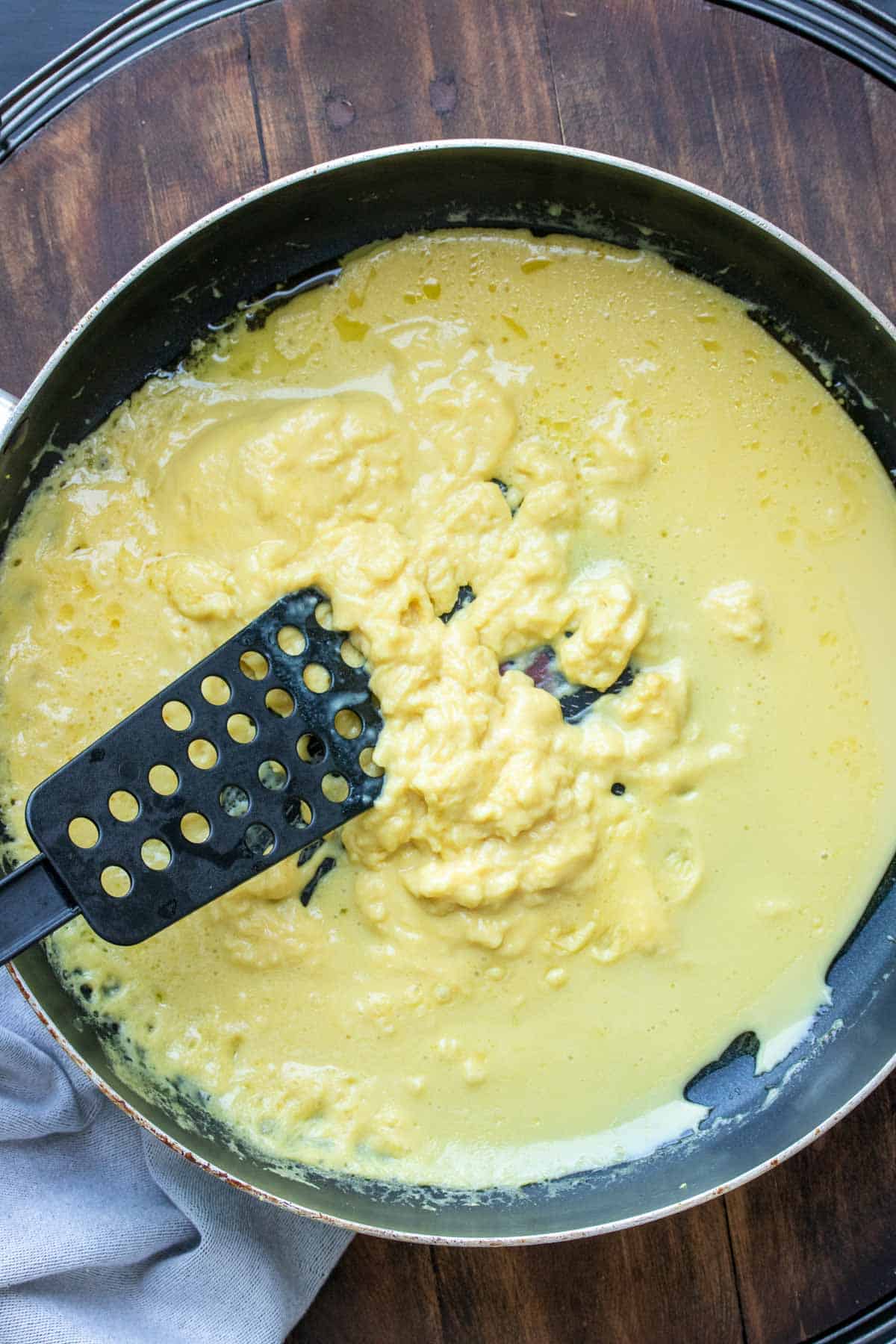 Spatula scrambling liquid eggs in a pan.