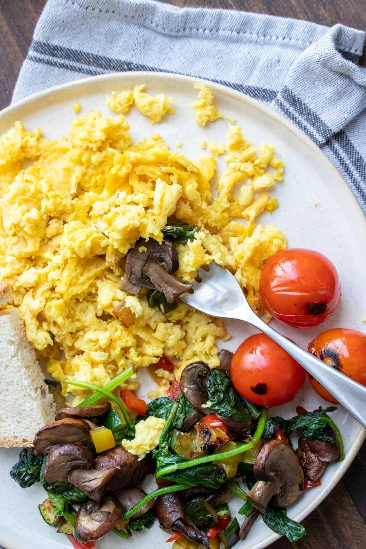 Fork getting a bite of scrambled eggs from a plate