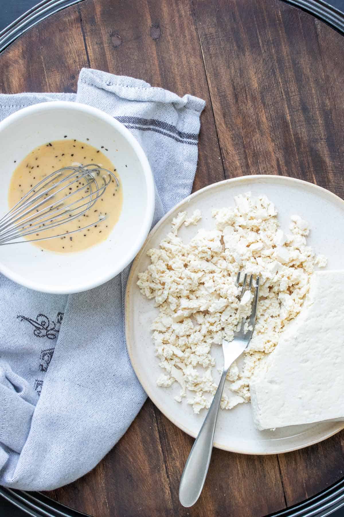 Plate of chopped up tofu next to a bowl of whisked liquid.