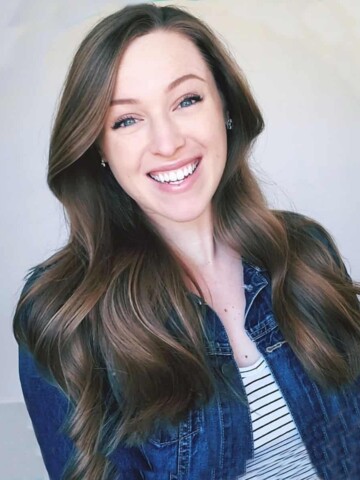 Woman smiling with long brown hair wearing a jean jacket over a striped shirt