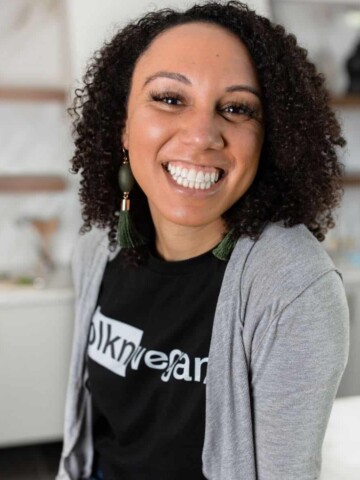 A woman with black curly hair to her shoulders smiling at the camera