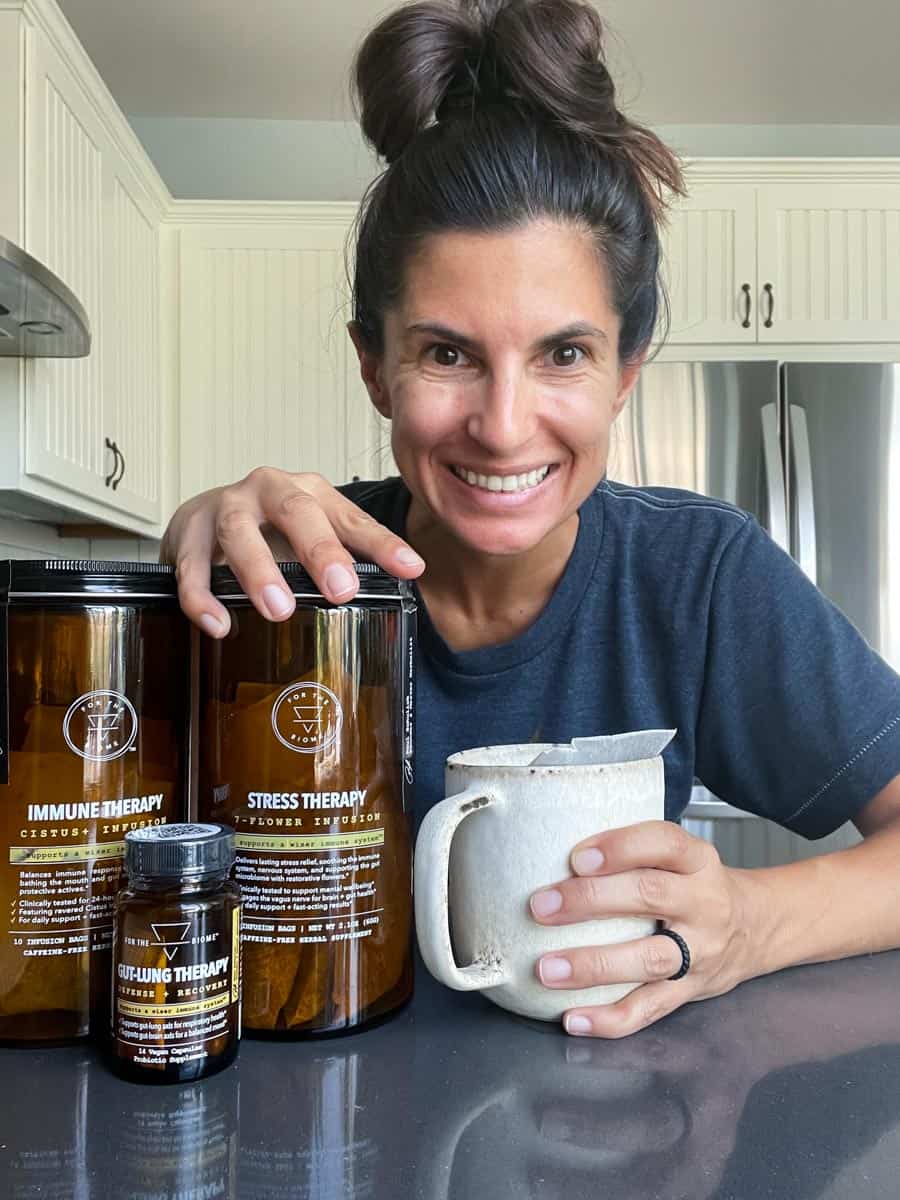 Woman smiling holding a mug with her hand on tall amber containers