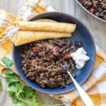 Blue bowl with a black bean and rice mixture in it on a yellow and white checkered towel.