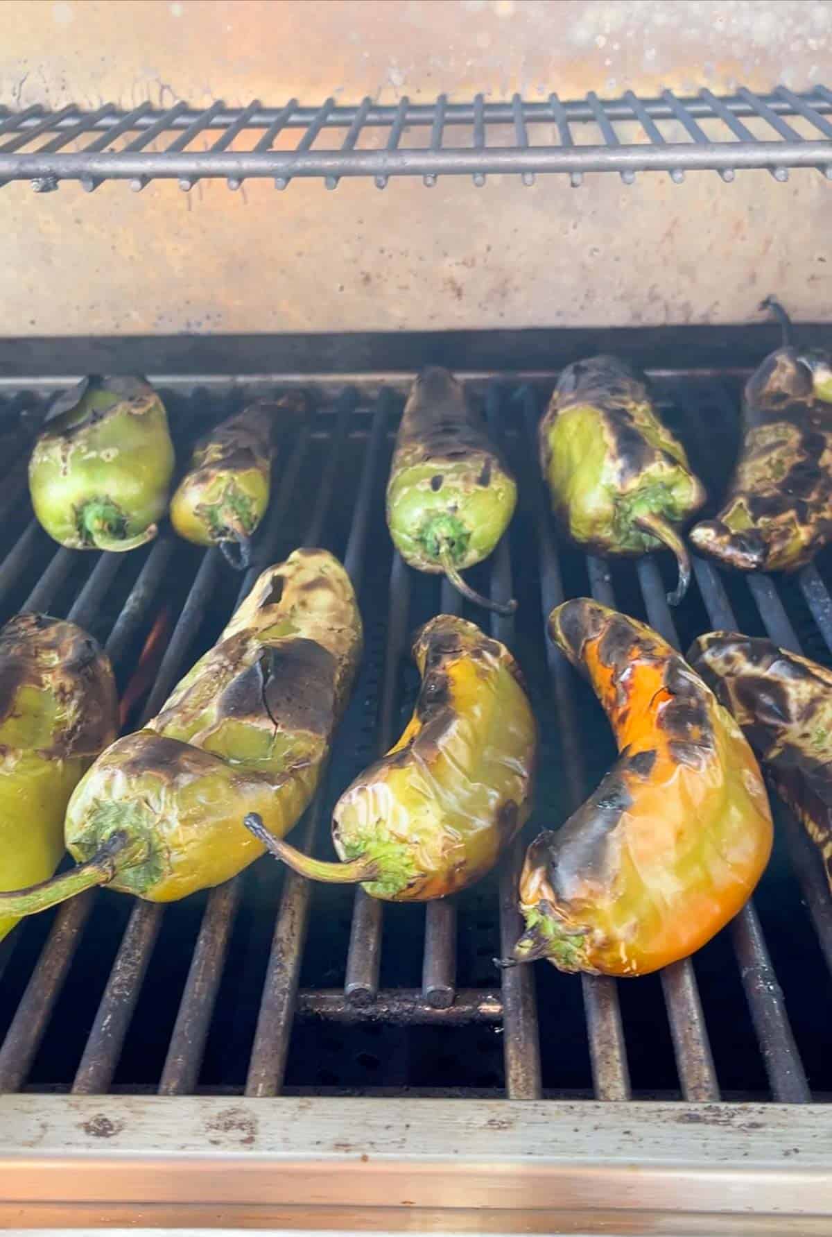 Red and green peppers being roasted on an outside grill