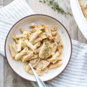 Cream bowl with a creamy pasta dish topped with crispy breadcrumbs on a wooden surface