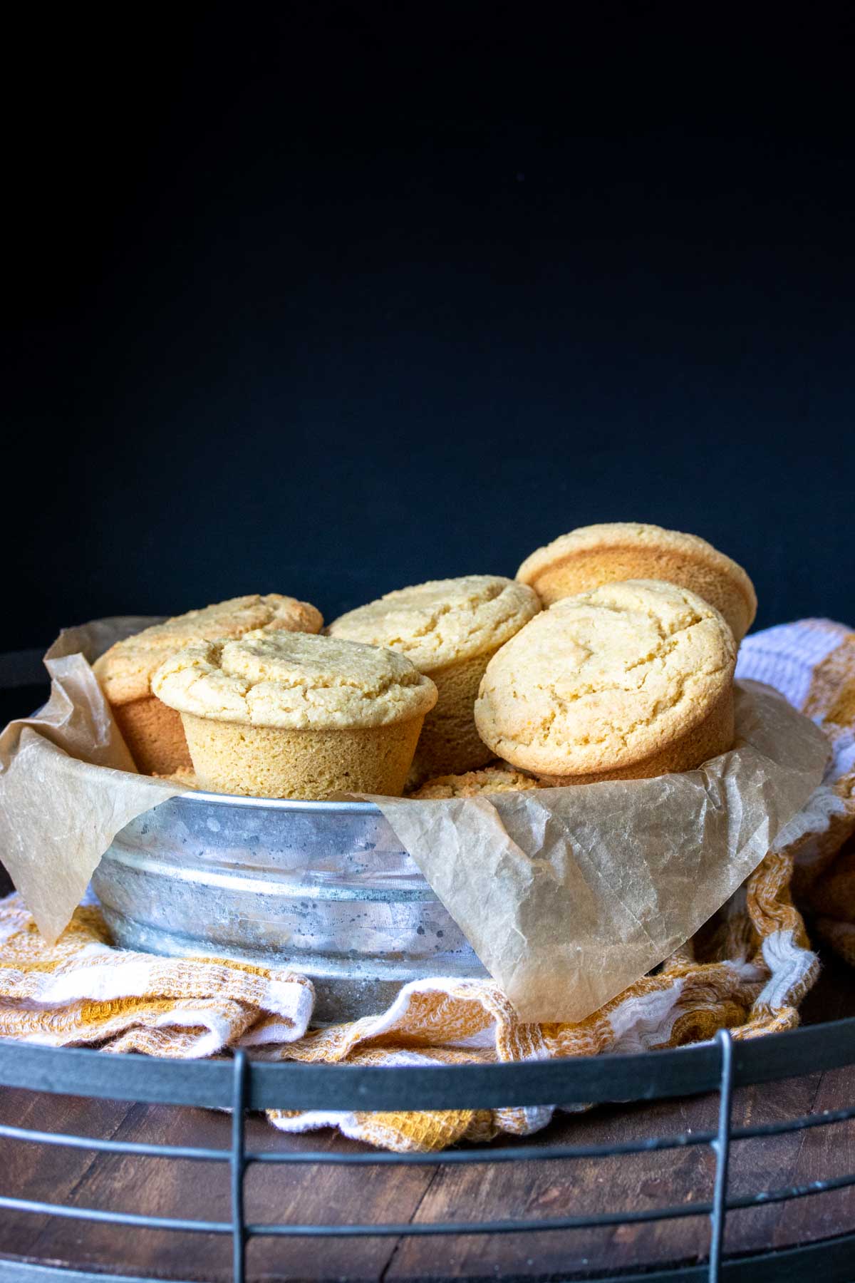 Yellow muffins piled in a metal bowl with parchment paper in it