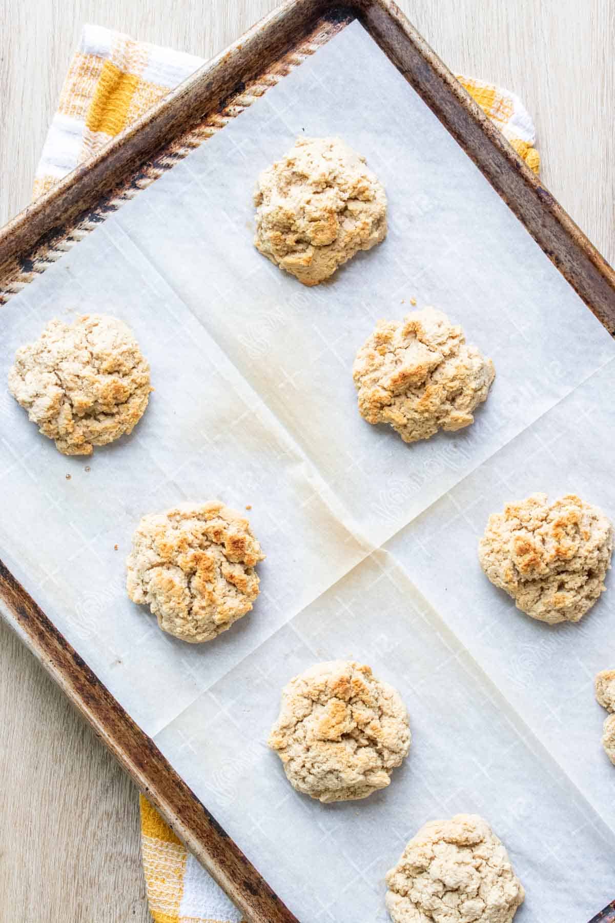 Baked drop biscuits on a piece of parchment paper on a baking sheet