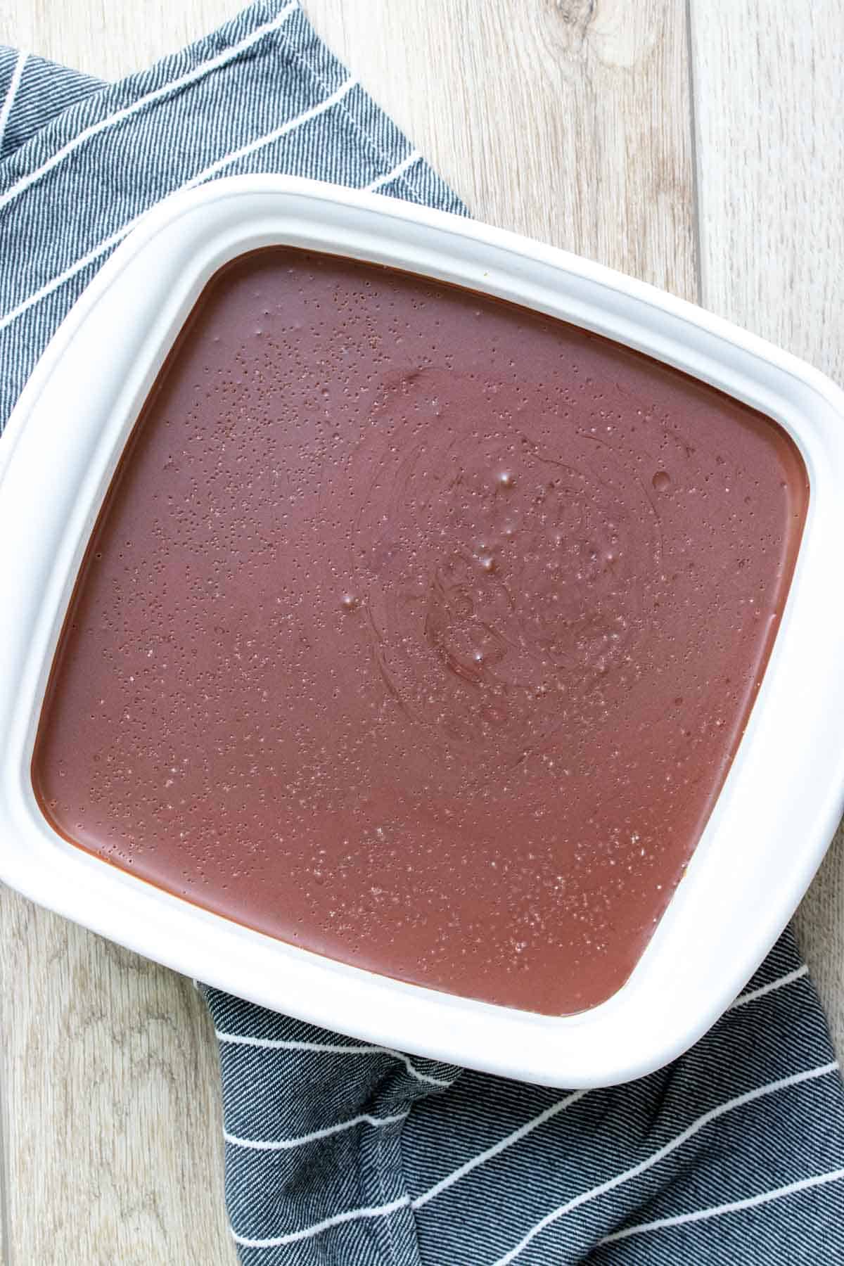 The top view of a square white baking dish with firm chocolate ganache in it