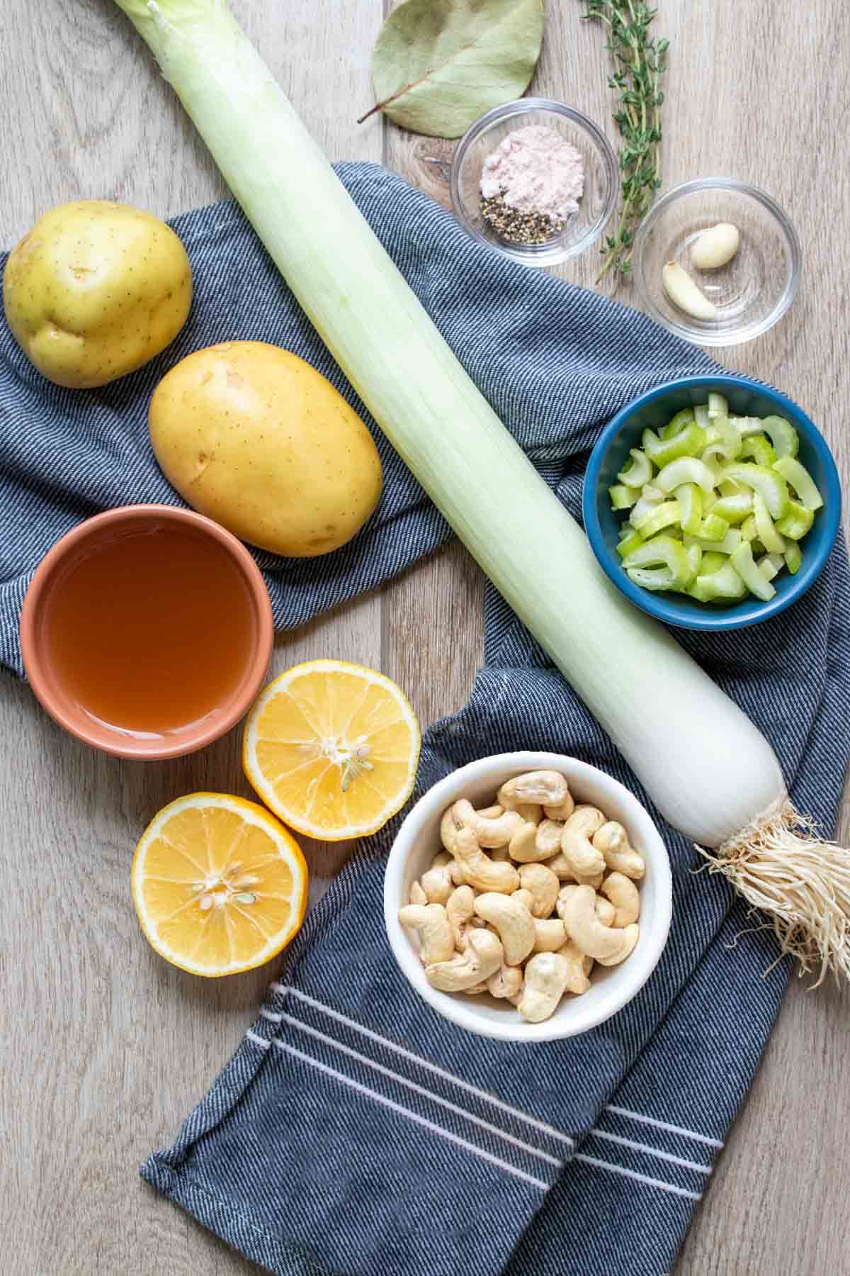 Ingredients needed to make a cashew cream potato leek soup on a dark blue towel