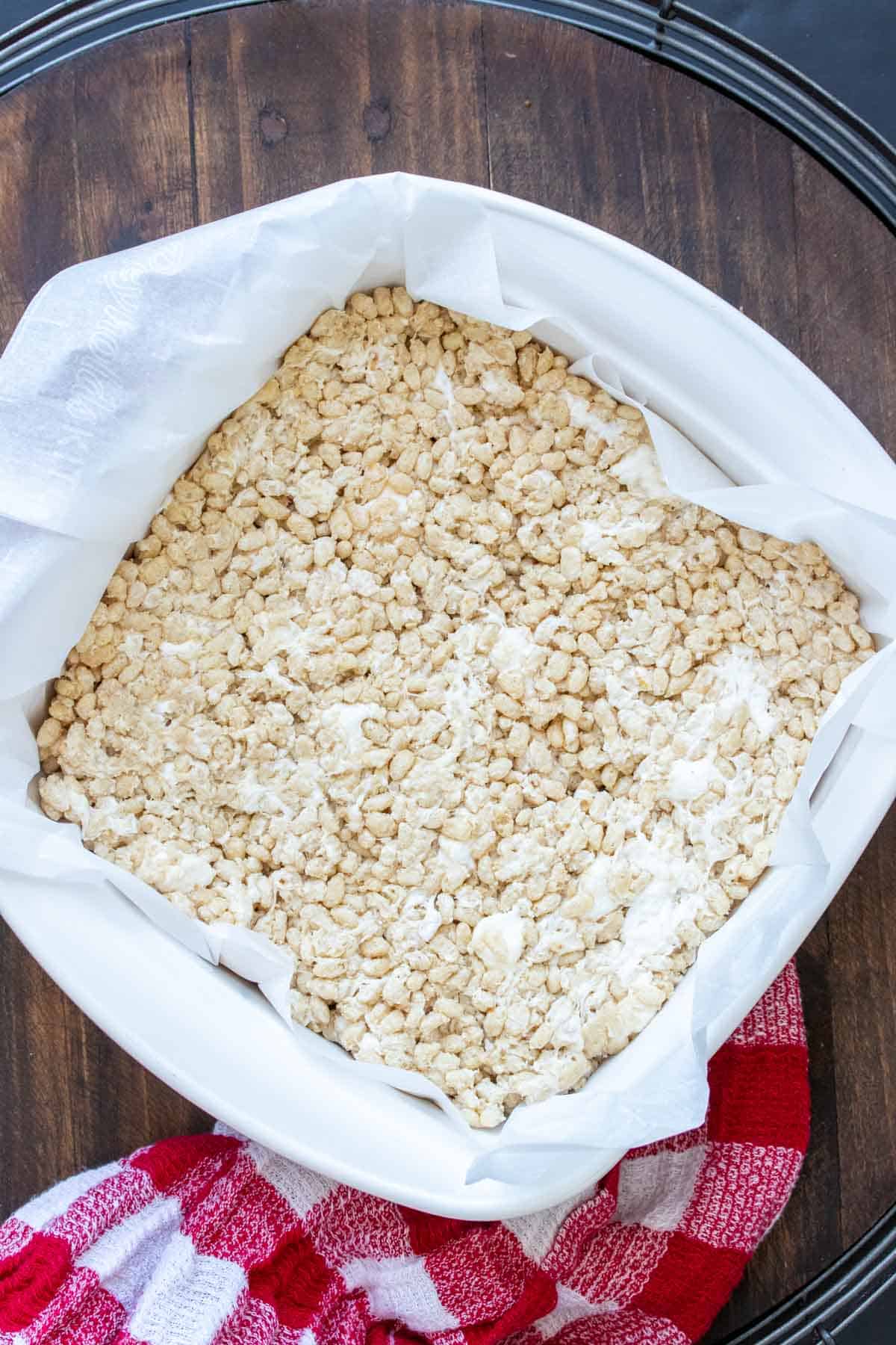 Top view of a square baking dish with rice krispie treats in parchment paper