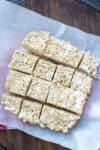 Parchment paper with cut rice krispie treats on top on a wooden surface