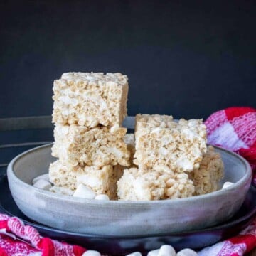 Grey plate with a pile of rice krispie treat squares on a checkered towel