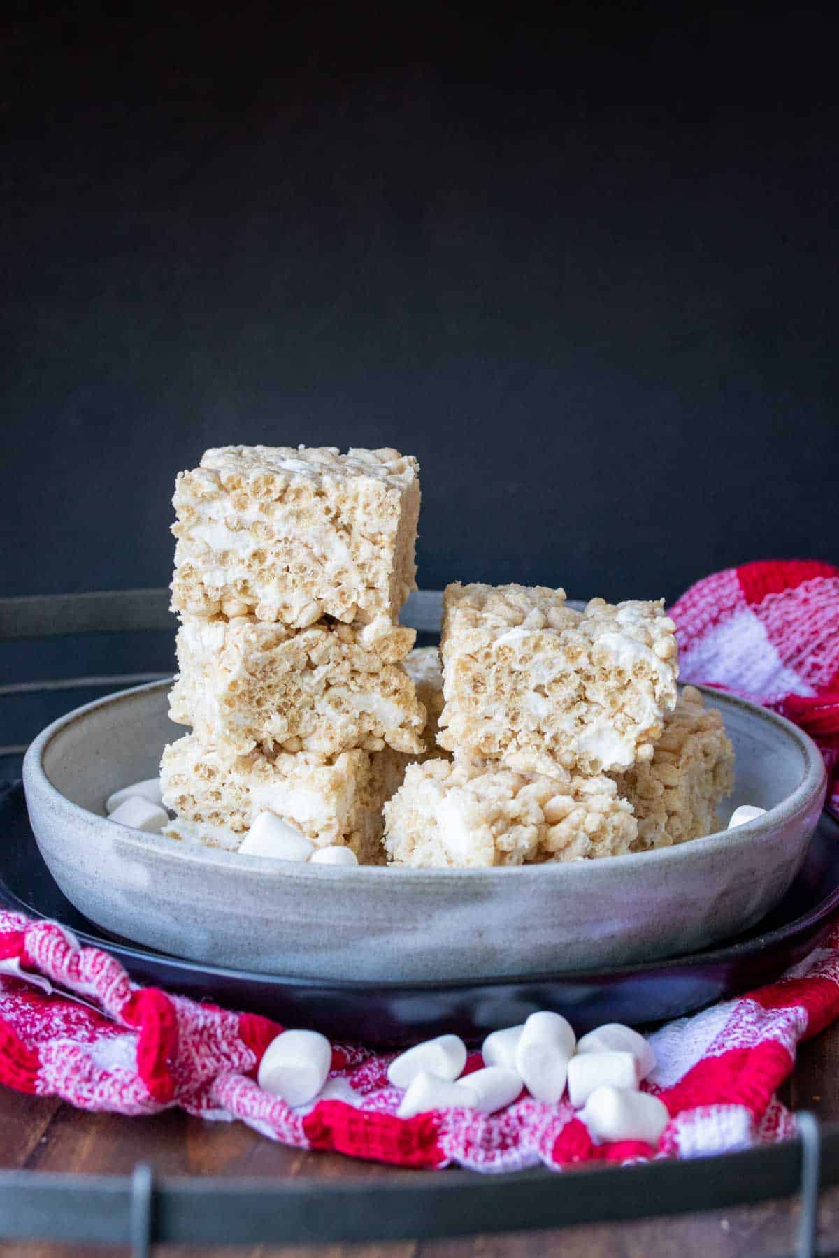 Grey plate with a pile of rice krispie treat squares on a checkered towel