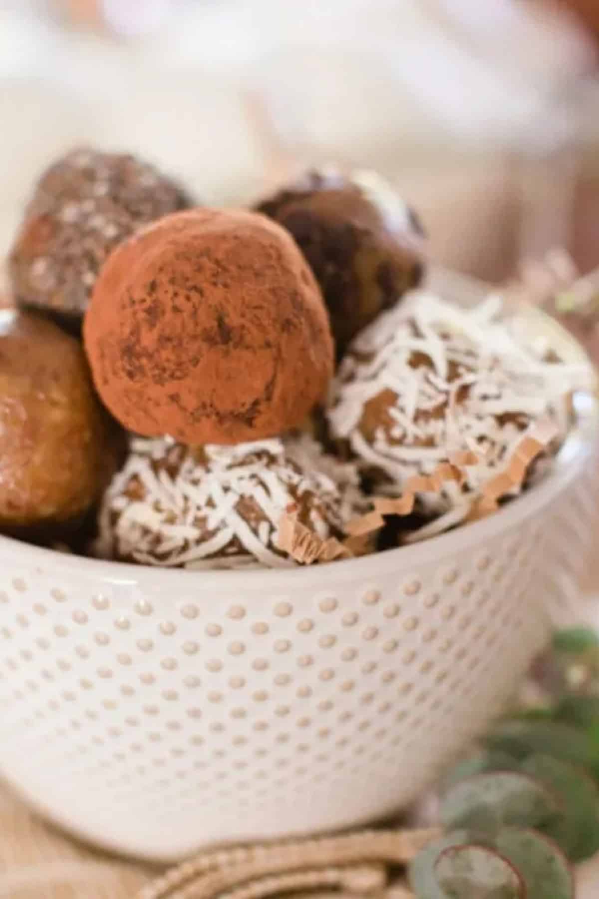 White textured bowl with truffles covered in cocoa and coconut flakes