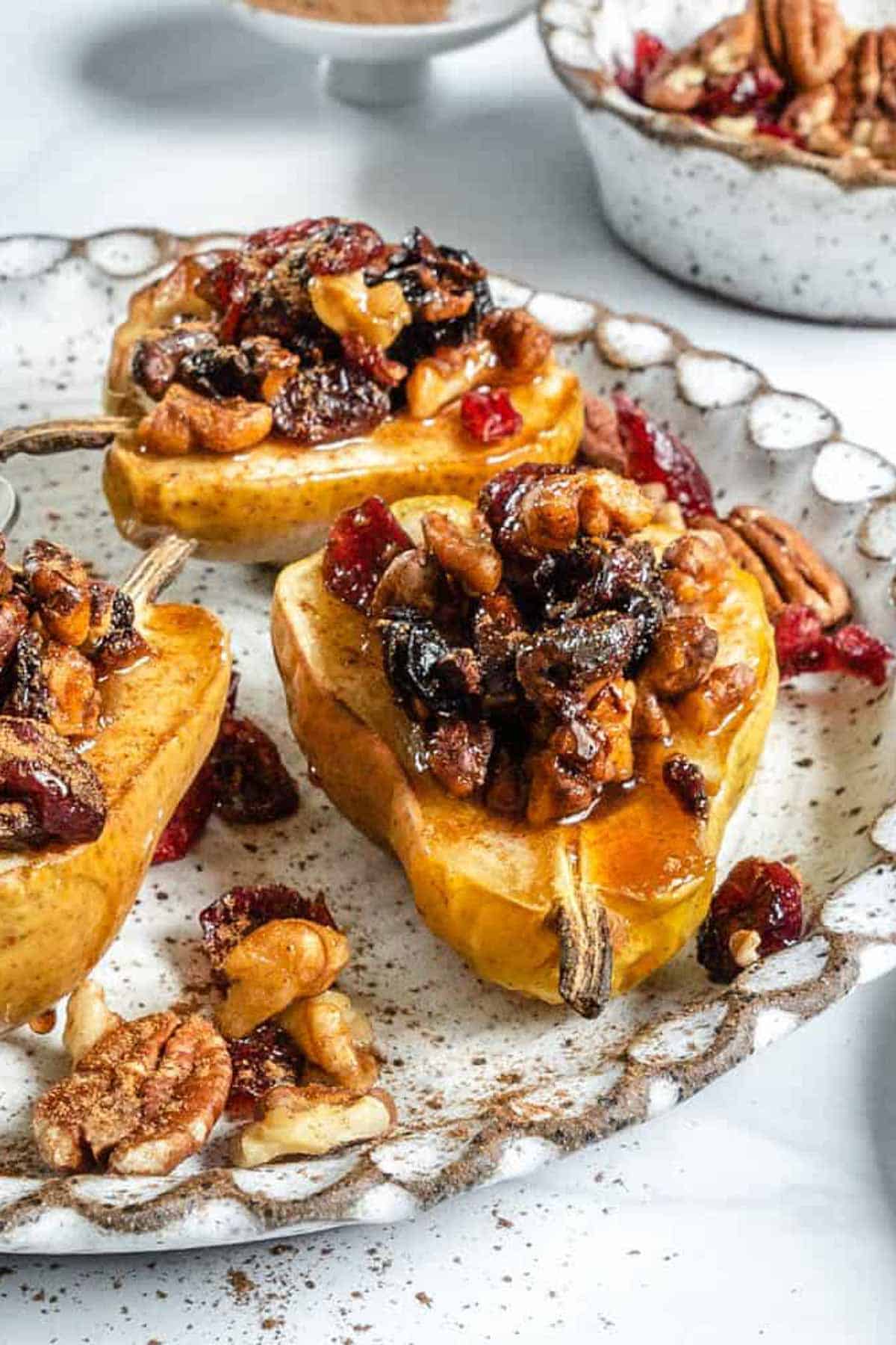White textured plate with baked pears topped with dried fruit and nuts