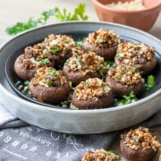 A black plate in a grey plate on a darker grey towel with stuffed appetizer mushrooms in it