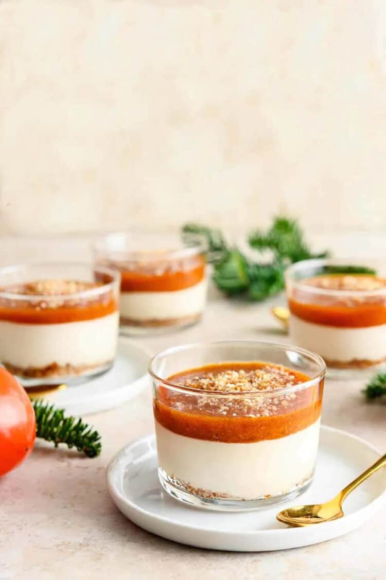 Clear jars with layered white and orange pudding inside on a cream surface