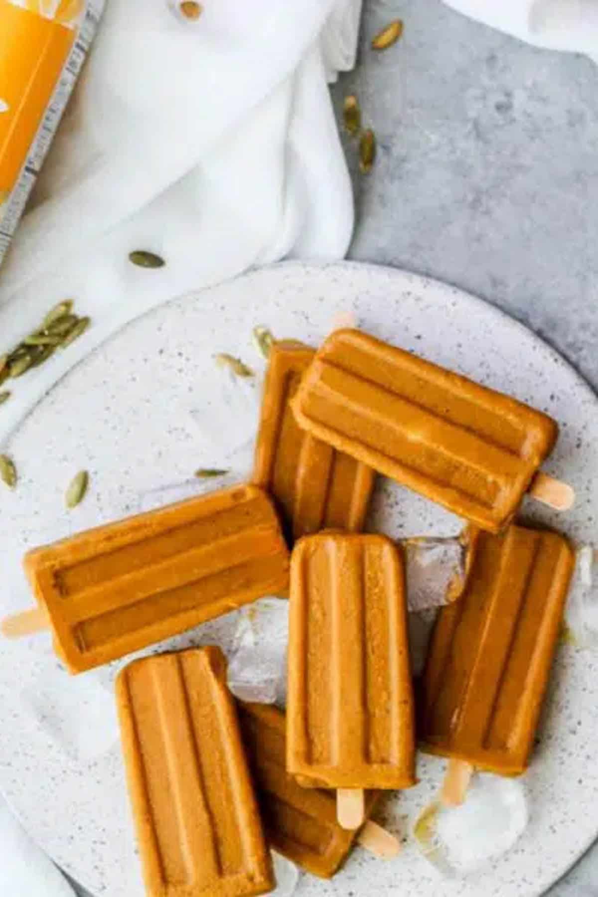 White plate with pumpkin popsicles piled on it