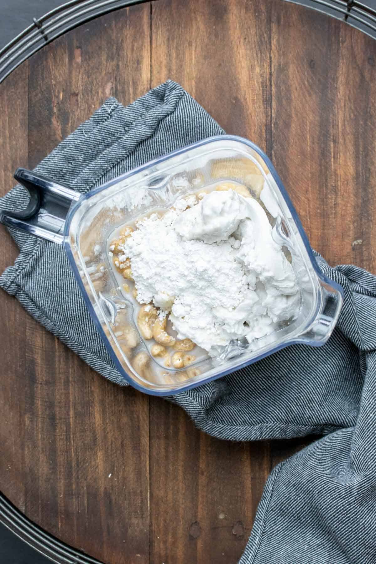 Top view of a blender with cream, cashews and other ingredients to make a dairy free pudding